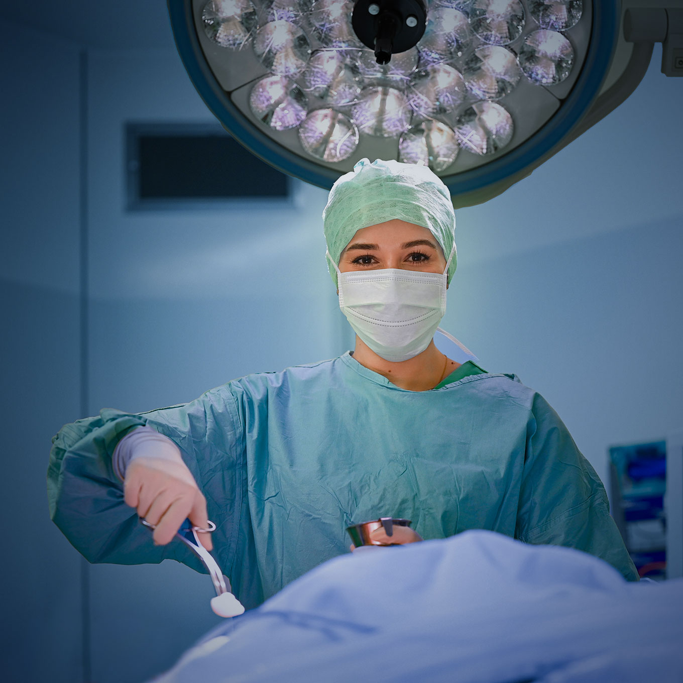 Operationstechnische Assistentin hält einen Tupfer in der Hand und grinst freundlich in die Kamera 